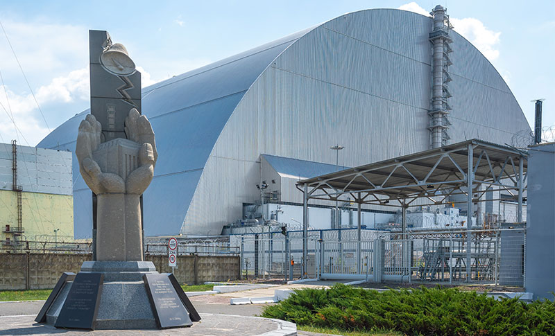 Atomkatastrophe von Tschernobyl. Sarkophag des zerstörten Blocks 4 und Denkmal. Foto: Adobe Stock | Diego Grandi